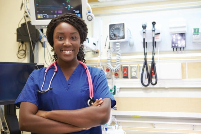 A nurse stands with her arms crossed in front of medical equipment