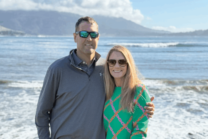 Man and woman on a beach with mountains and waves in the background