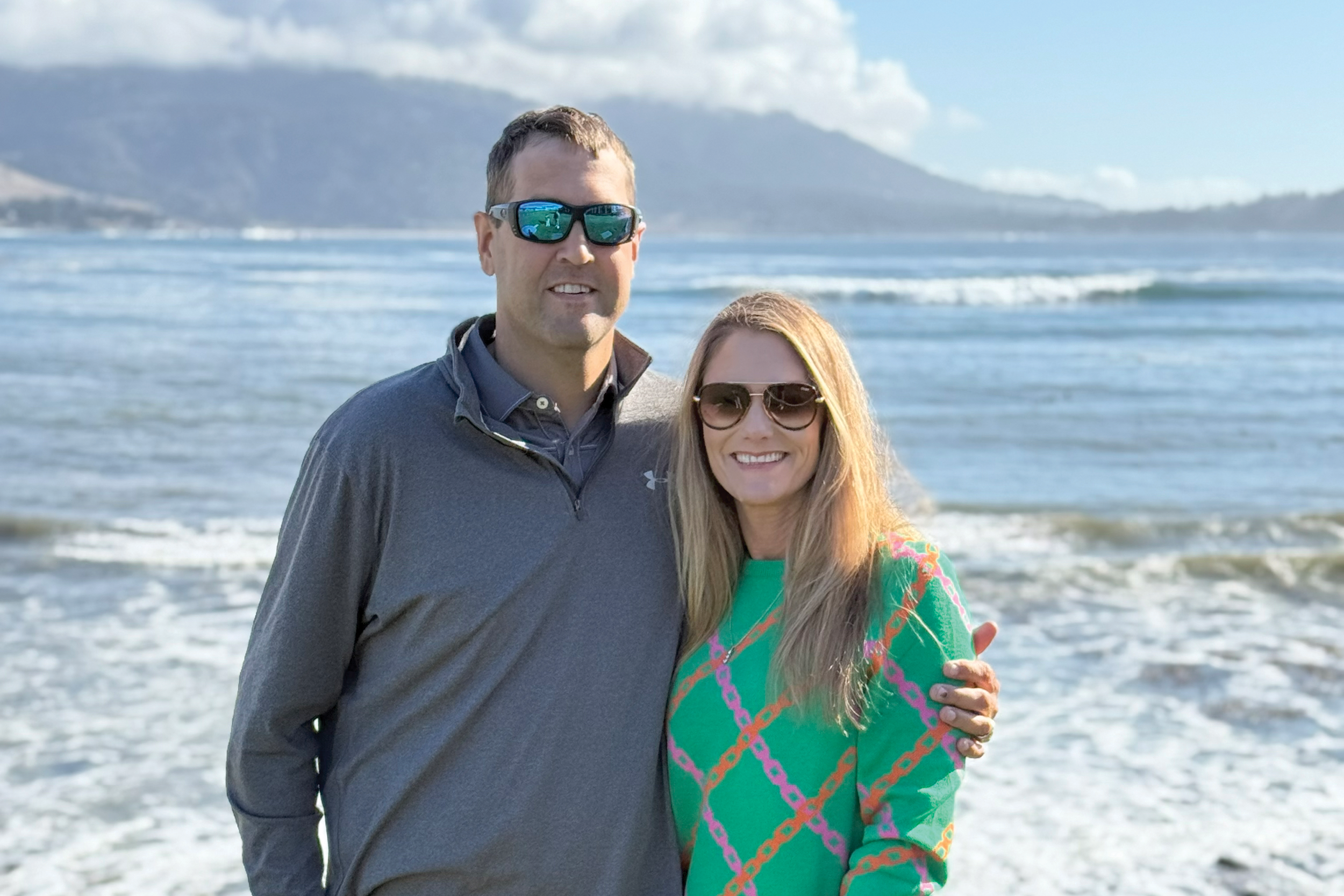 Man and woman on a beach with mountains and waves in the background