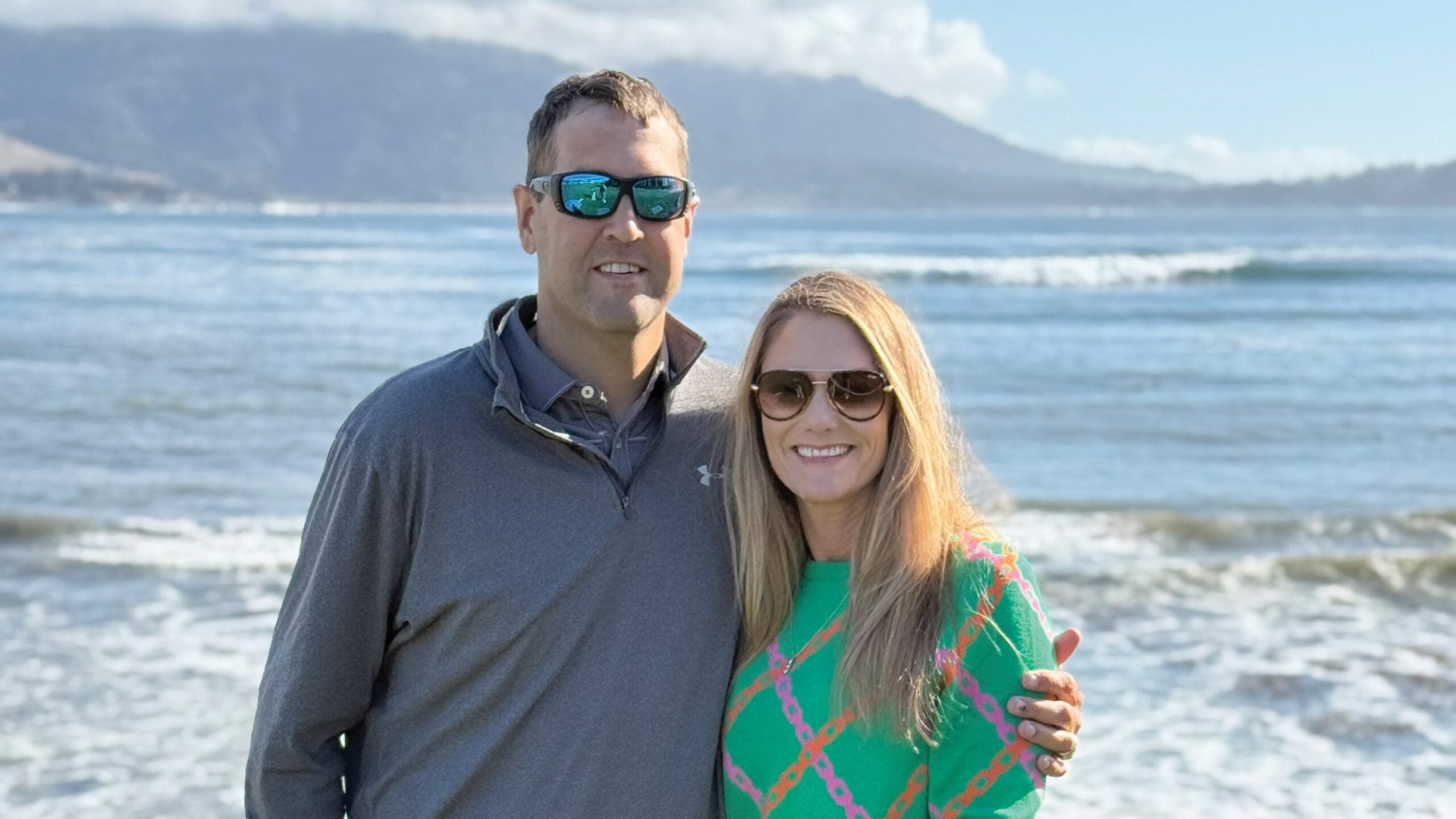 Man and woman on a beach with mountains and waves in the background