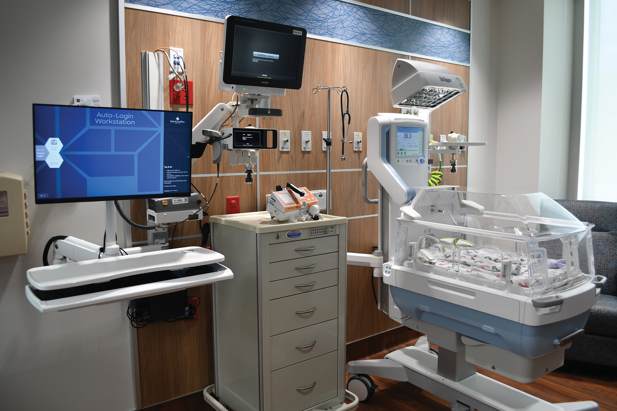 NICU station with an incubator, monitors, and medical equipment for newborn care.