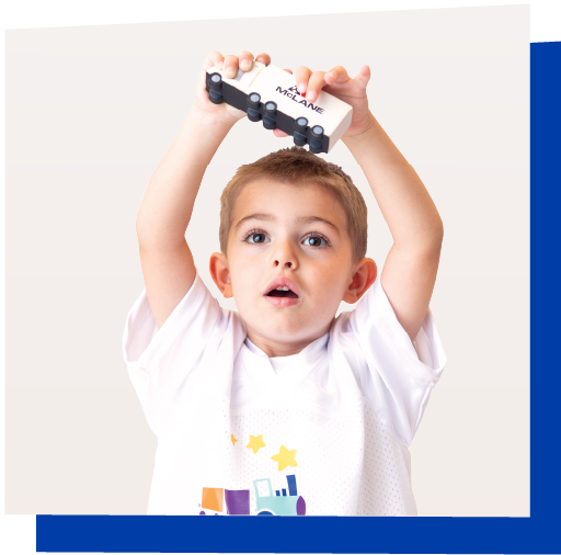 Three year old wearing a McLane Children's football jersey holds up a toy 18-wheeler with the McLane Company logo on the side.